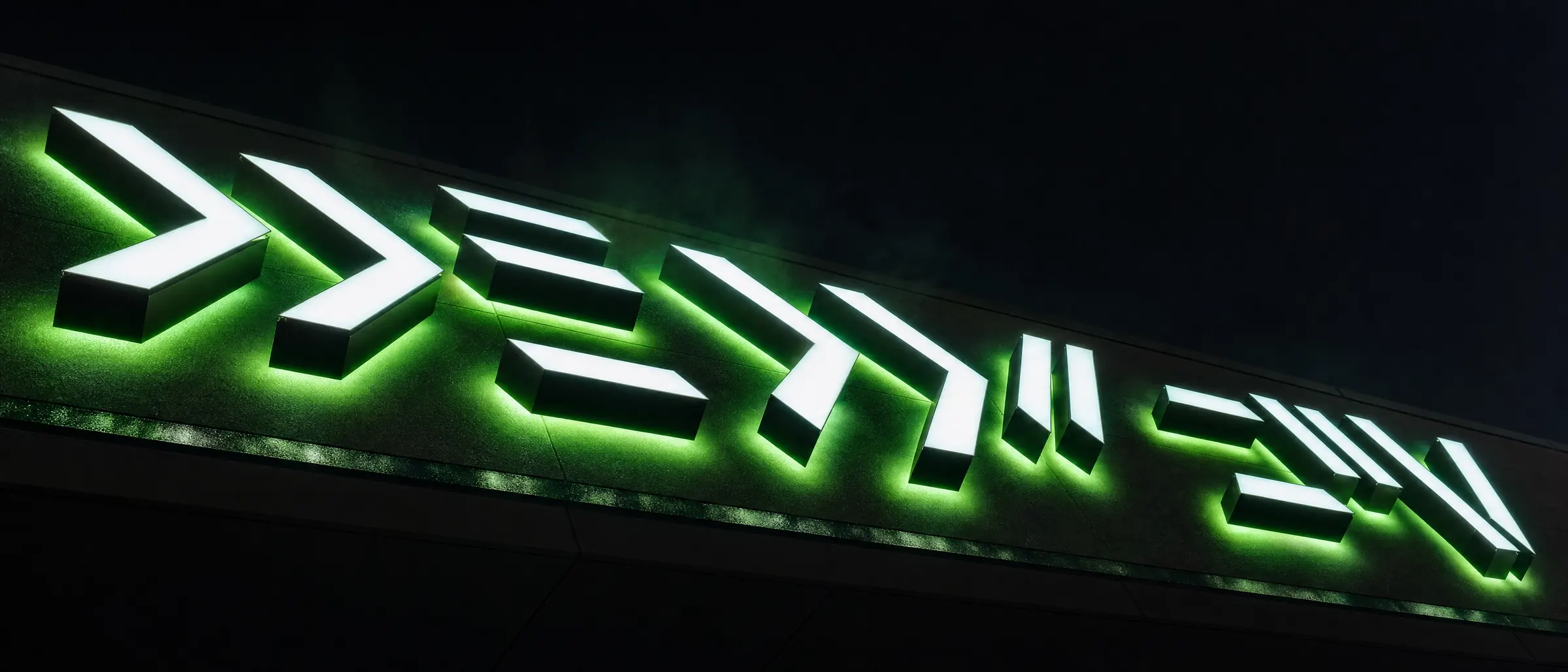 Illuminated fabricated signage glowing on a building at night.